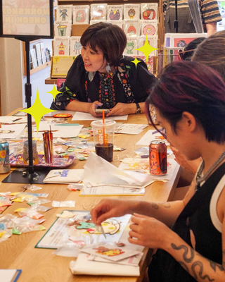 naoshi helping people with their sand art in a workshop