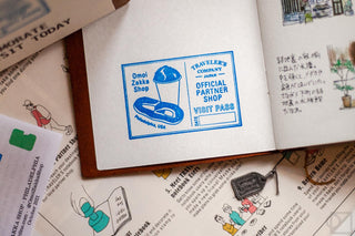 A blue ink stamp on a journal page that says Omoi Zakka Shop Visit Pass with an illustration of Philly pretzel and water ice