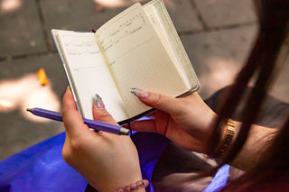 A close-up shot of J holding open the Laconic B7 Pocket Log Diary with both hands. In their left hand is a purple pen.