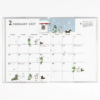 A6 monthly planner open to February 2027 calendar with frog and animal scenes