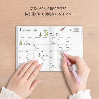 A6 monthly planner with hands marking dates on the January 2027 calendar
