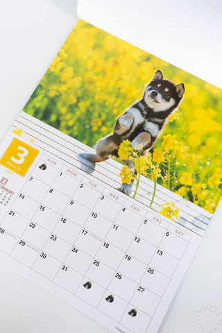 calendar page featuring a photo of a puppy sitting among bright yellow flowers, with a monthly calendar grid below