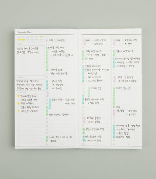 Open planner with handwritten notes and colorful highlights on a gray background