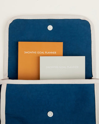 Blue pouch with orange and gray '3 Months Goal Planner' planners inside on a white background