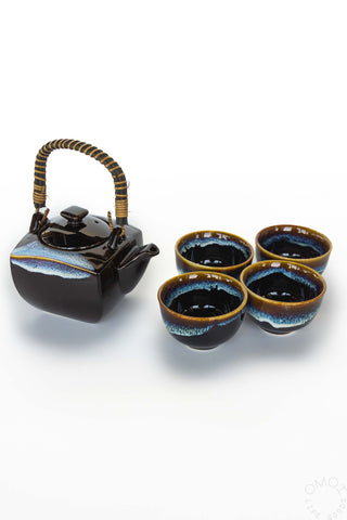 Ceramic teapot with four matching cups on a white background