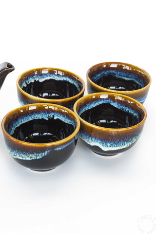 Set of four ceramic cups with blue and brown glaze on a white background