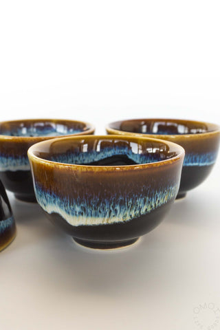 Set of ceramic tea cups with a blue and brown rim on a white background