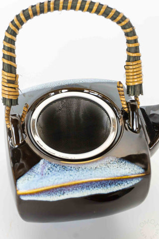 Ceramic teapot with strainer and bamboo handle on a white background