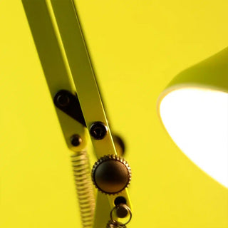 Close-up of green desk lamp with metal components on a yellow background