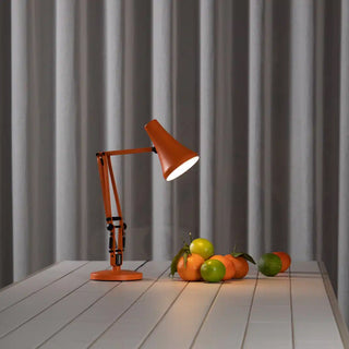 Orange desk lamp on a tile surface with fruits against a gray curtain background