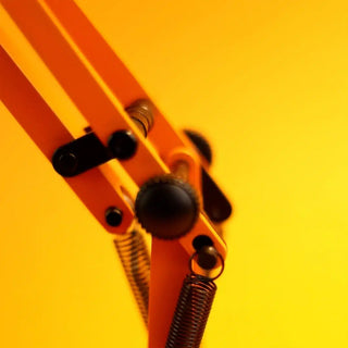 Close-up of the mechanics of the Anglepoise lamp with springs on a yellow background