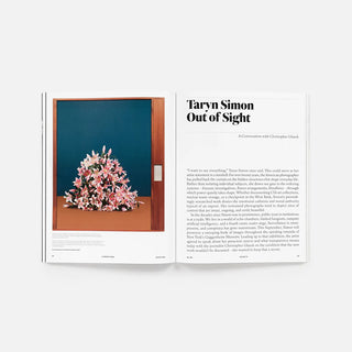 Magazine spread features a photograph of pink flowers against deep teal-blue wall with text on the right page.