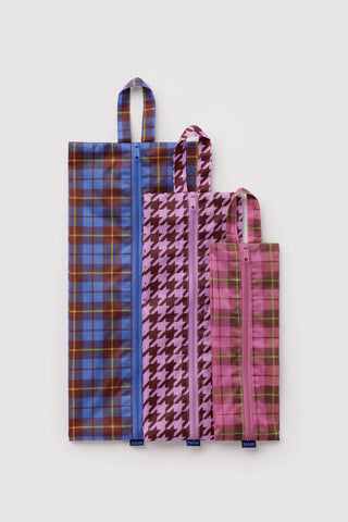 3d zip set of packing pouches in colorful tartan and houndstooth patterns laid flat on a light background
