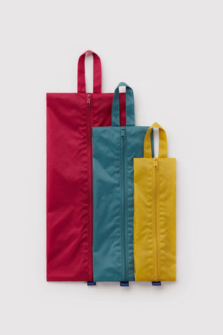 3d zip set of packing pouches in red, green, and yellow laid flat on light background