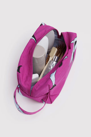Pink toiletry bag with travel items on a white background