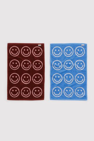 Set of baggu hand towels with smiley face pattern. one in red and pink colorway and other in blue and white colorway