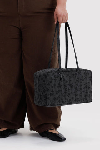 person holding baggu medium bowler bag in black floral pattern in their hand