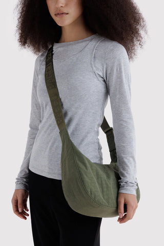person wearing baggu medium crescent bag in caper green across their body