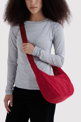 person wearing baggu medium crescent bag in cherry red across their body
