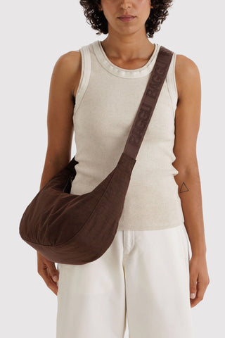 person wearing baggu medium crescent bag in coffee brown across their body