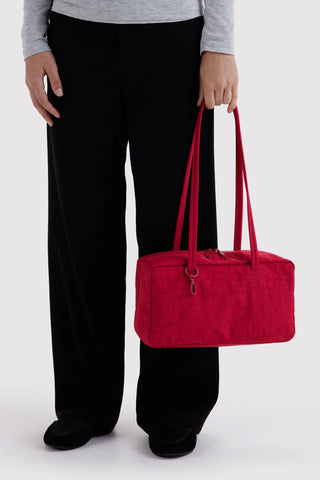 person holding nylon bowler bag in cherry red colorway in their hand