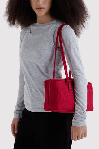 person wearing gray shirt and wearing nylon bowler bag in cherry red colorway on their shoulder