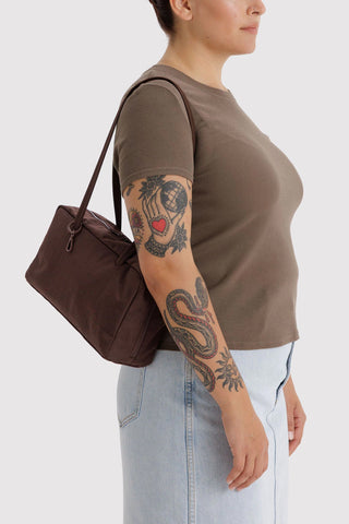 person wearing nylon bowler bag in coffee brown colorway on their shoulder