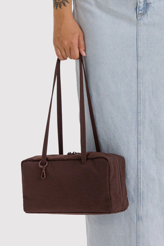 person holding nylon bowler bag in coffee brown colorway in their hand
