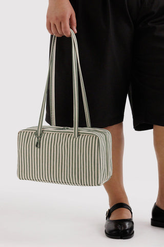 Person holding a striped handbag against a white background