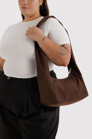 Person wearing a brown shoulder bag on a white background