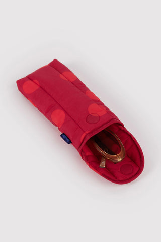 puffy glasses sleeve in red polka dot pattern opened with sunglasses inside on a light background