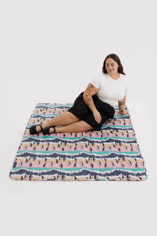 Woman sitting on a colorful patterned blanket against a white background
