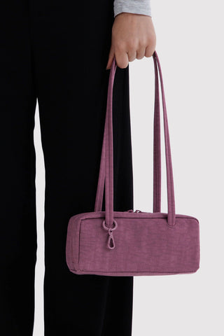 person holding small bowler bag in wild plum in their hand