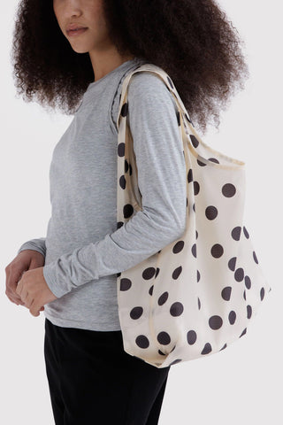 person wearing standard black and cream polka dot baggu tote on their shoulder