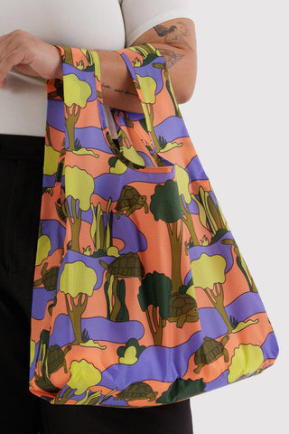 Colorful turtle patterned bag held by a person on a white background