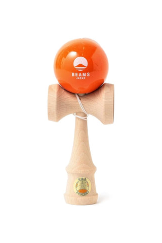 Wooden kendama with an orange ball featuring the beams japan logo on a white background