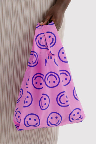 Baby BAGGU pop pink tote bag held open, smiley face print