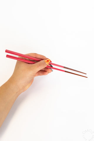 Hand holding red chopsticks on a white background