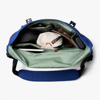 Open blue messenger bag with items inside on a white background