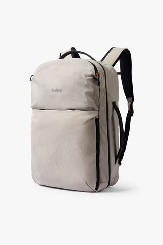 A light beige backpack with black straps and zippers, set against a plain white background.