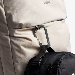 Close-up of a beige backpack with a black strap and carabiner, featuring 'bellroy' branding