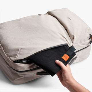 Beige backpack with an open compartment and hand taking out separate bag