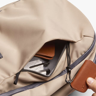 Close-up of stone-beige workpack with zipper, drawcord, and leather-trim pocket.