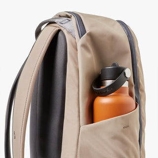 Side view of stone-beige workpack with adjustable strap and bottle pocket.