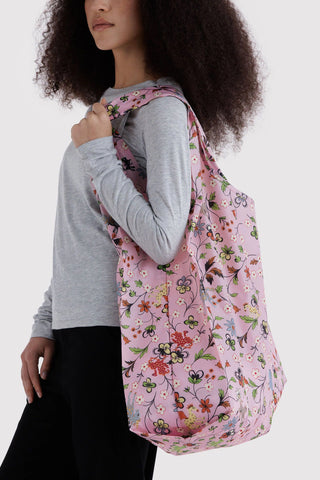person wearing big pink baggu tote with flowers and animals print on their shoulder