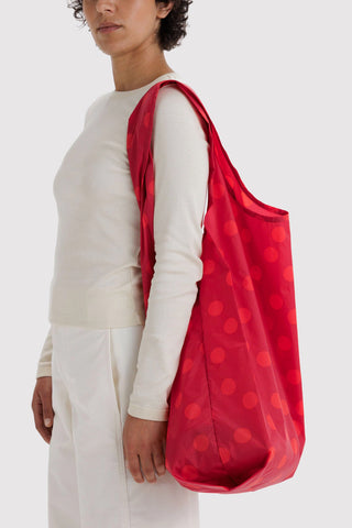 person wearing big baggu red polka dot tote on their shoulder