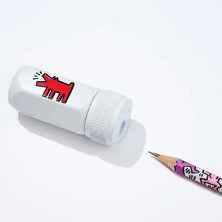 White pencil sharpener with red cartoon dog design next to a pencil with pink and black design on a white background