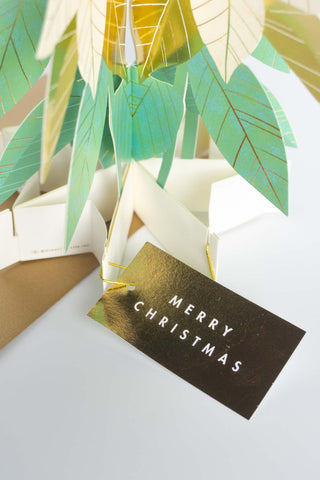 Christmas card with green leaves and a gold 'Merry Christmas' tag on a white background