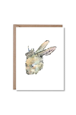 greeting card with a brown kraft envelope, featuring a whimsical illustration of a rabbit wearing a small cake on its head