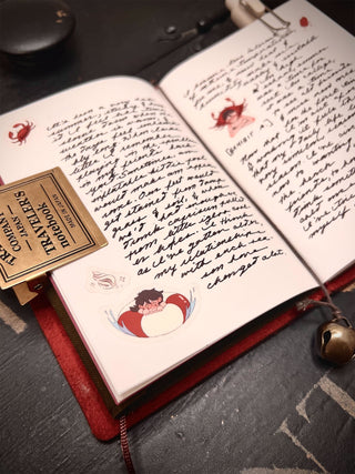 Open notebook with stickers and handwritten text on a dark surface